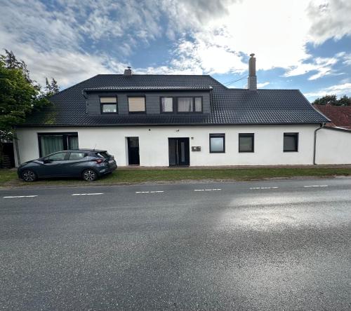 a white house with a car parked in front of it at Ferienwohnung auf dem Land in Grethem