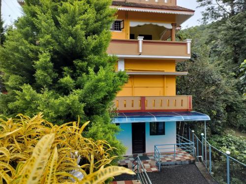 a yellow and blue building with a tree at Allora homestay in Vagamon