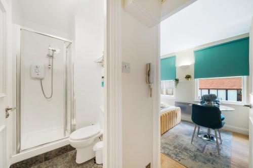 a bathroom with a shower and a toilet and a bedroom at Stylish Studios in Historic City of London, Next to Barbican & Farringdon in London