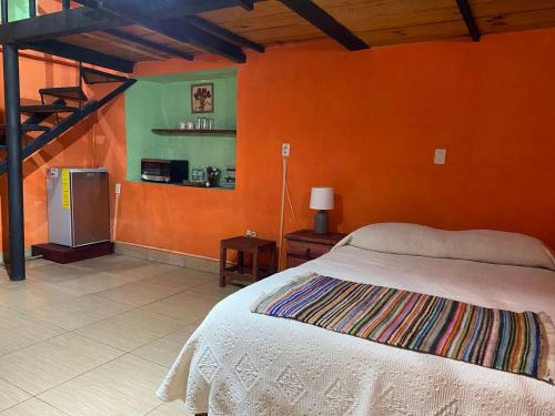 ein Schlafzimmer mit einem Bett und einer orangefarbenen Wand in der Unterkunft Espacio privado muy cerca del centro in Guanajuato