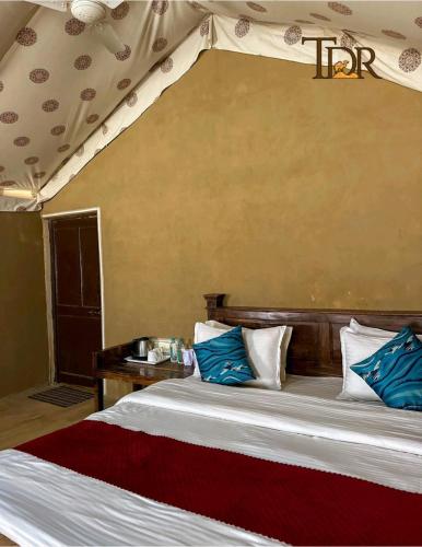 a bedroom with a bed with blue and white pillows at The Desert Resort Jaisalmer in Jaisalmer