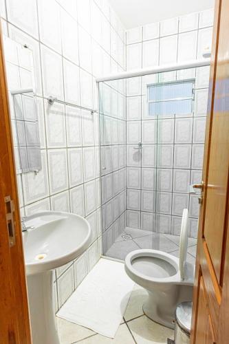 a white bathroom with a toilet and a sink at SWAMY HOTEL ANEXO I in Cruzeiro do Sul