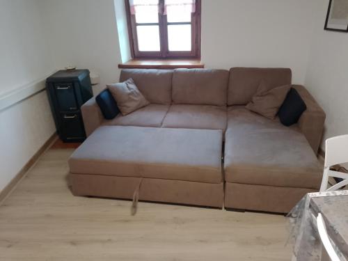 a brown couch in a living room with a window at Pila Petit Coin Gerdaz Les Fleurs SKI & MTB in Cerise