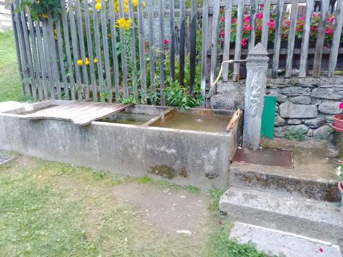a fence with a water trough in front of a garden at Pila Petit Coin Gerdaz Les Fleurs SKI & MTB in Cerise