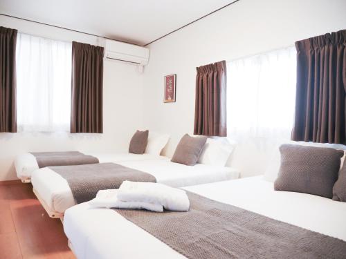a hotel room with three white beds and windows at 9Stay西浅草 in Tokyo