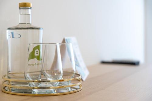 a bottle of wine and two glasses on a table at Ápice - by Azores Green Villas in São Vicente Ferreira