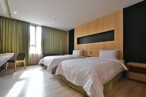 a hotel room with two beds and a desk at Hotel R14 in Kaohsiung