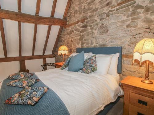 a bedroom with a bed with two lamps and a stone wall at Courtyard Cottage in Church Stretton