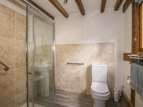 a bathroom with a toilet and a glass shower at Courtyard Cottage in Church Stretton
