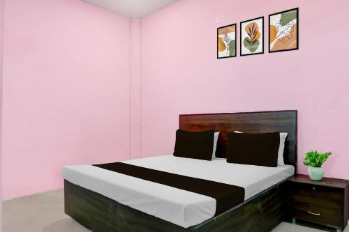 a bedroom with a large bed in a pink room at SPOT ON Mahal Guest House in Paikbara