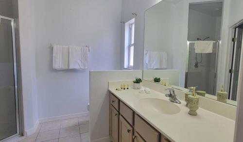 Un baño blanco con lavabo y espejo. en Magical Way, en Kissimmee