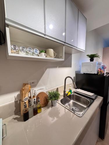 a kitchen counter with a sink and a microwave at Casa Lyra Staycation Trees Residences in Manila