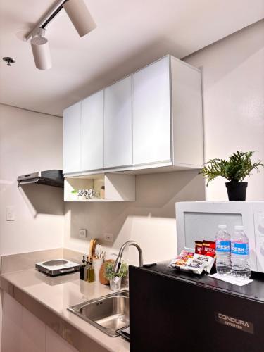 a kitchen with white cabinets and a sink at Casa Lyra Staycation Trees Residences in Manila