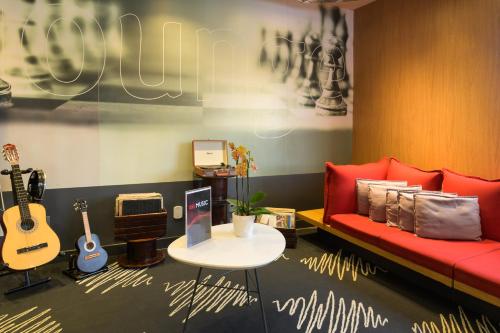 a living room with a red couch and some guitars at ibis Aracaju in Aracaju