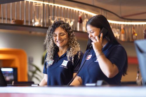 two women smiling while talking on a cell phone at ibis Styles Fortaleza Shopping Giga Mall in Fortaleza