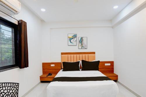 a bedroom with a bed with white walls and a window at Hotel O Avaanti in Pune