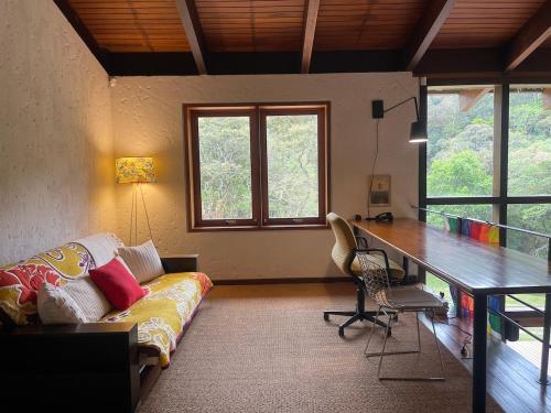 a living room with a couch and a desk at Reserva Atibaia / Casa de Montanha in Atibaia