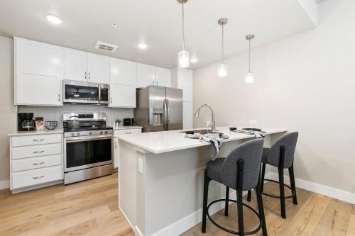 Northfield Old Town Flat with Attached Garage and EV في Buckingham: مطبخ مع دواليب بيضاء وجزيرة مطبخ مع كراسي بار