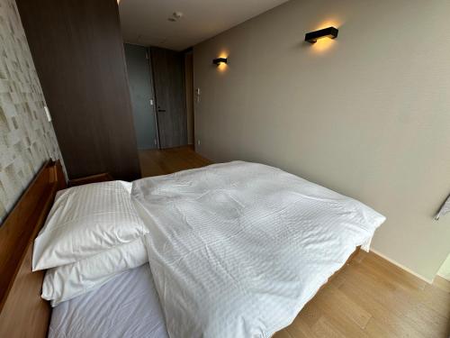 a bedroom with a white bed with two lights on the wall at SuiShou in Kutchan