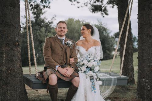 a bride and groom sitting on a swing at The Gailes Hotel & Spa in Irvine