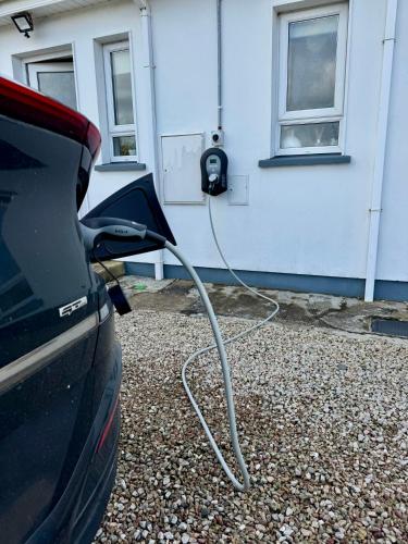 a car is hooked up to a car charger at Mountain View Cottage - Style, Calm & Scenery EV Friendly Zappi in Ray
