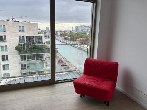 a red chair in a room with a large window at Top floor luxury with spectacular water views in Brussels