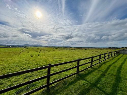a fence in front of a green field with cows at Mountain View Cottage - Style, Calm & Scenery EV Friendly Zappi in Ray