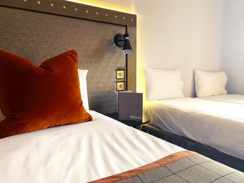 a hotel room with two beds and an orange pillow at The Gailes Hotel & Spa in Irvine