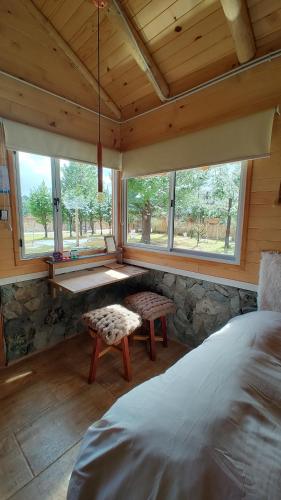 a bedroom with a bed and a bench and windows at Entre Cerros Tiny House Única in Moquehue