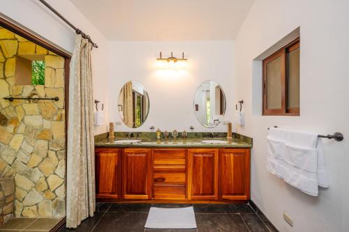 a bathroom with two sinks and two mirrors at Hacienda Pinilla Vacation Rentals in Tamarindo