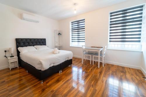 a bedroom with a bed and a desk and two windows at Centra High Road in London