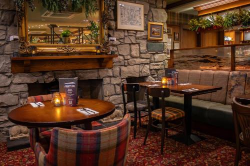 a restaurant with two tables and a stone wall at The Loans Inn in Troon