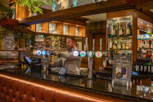 a bartender behind the counter of a bar at The Loans Inn in Troon