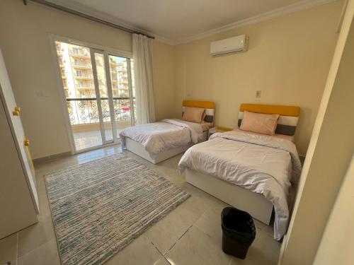 une chambre avec deux lits et une fenêtre dans l'établissement Cozy cheap apartment, à Burg el-Ḥudûd