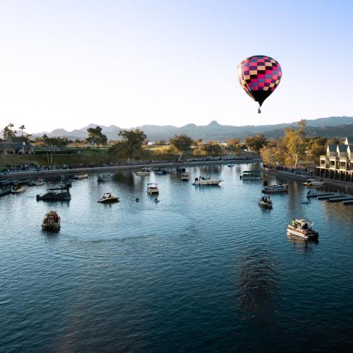 a hot air balloon flying over a river with boats at Paradise home with king bed & room for the family in Lake Havasu City