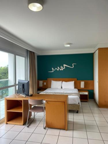 a bedroom with a bed and a desk with a computer at Praia do Canto Apart Hotel - Vista para o Mar 102A in Vitória