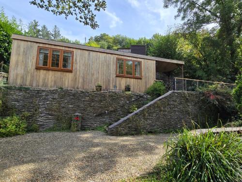 a wooden house with a stone wall and a staircase at Ty Barddu in Newcastle Emlyn
