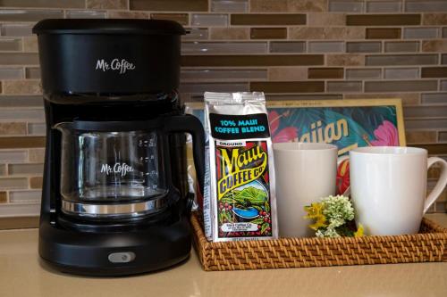 a coffeemaker and a coffee maker and cups on a counter at Mahana by KBM Resorts in Kaanapali