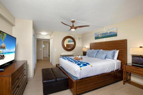 a bedroom with a large bed and a flat screen tv at Mahana by KBM Resorts in Kaanapali