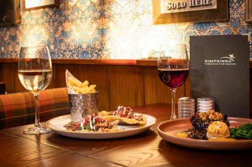 a table with two plates of food and two glasses of wine at The Loans Inn in Troon