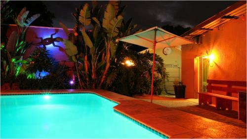a swimming pool with an umbrella next to a house at In Between Home in Lydenburg