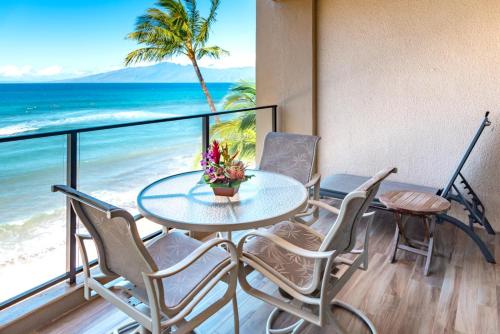 a table and chairs on a balcony with the beach at Mahana by KBM Resorts in Kaanapali