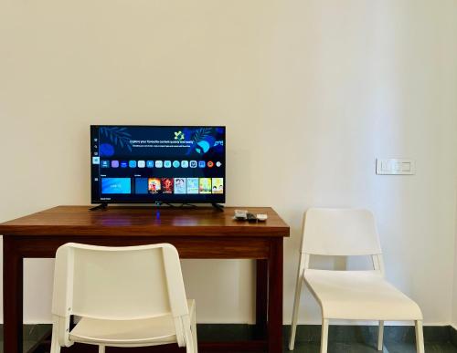 two white chairs sitting next to a desk with a television at Hill View Heights Wayanad in Meppādi
