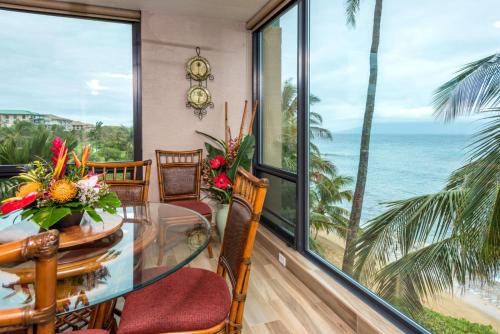 a dining room with a glass table and chairs and the ocean at Mahana by KBM Resorts in Kaanapali