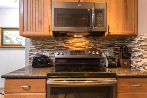 a kitchen with a stove and a microwave at Mahana by KBM Resorts in Kaanapali