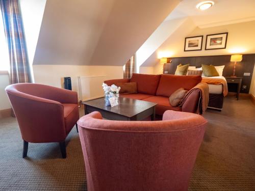 a hotel room with a couch and chairs and a bed at The Loans Inn in Troon