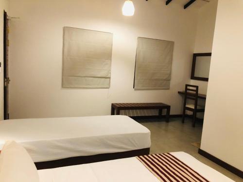 a bedroom with two beds and a table with a chair at Wild loch yala in Tissamaharama
