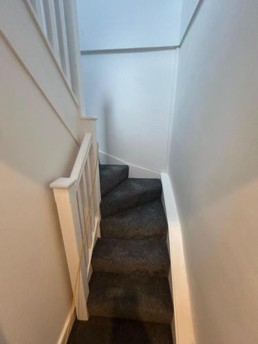 a staircase in a home with white walls and gray stairs at 3 Double Bedroom Home-Sleeps 8 - Castle Donnington in Castle Donington