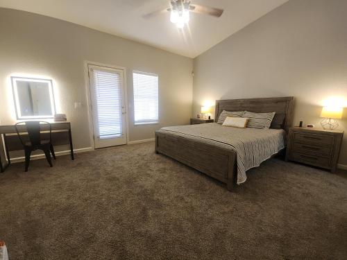 a bedroom with a bed and a desk and two windows at Paradise home with king bed & room for the family in Lake Havasu City