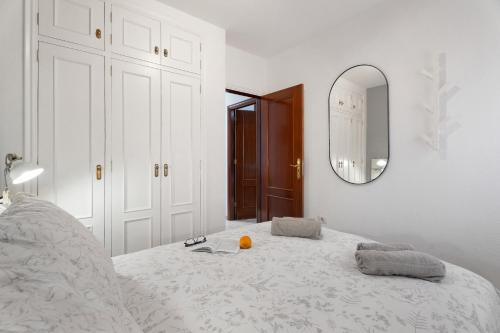 a white bedroom with a bed with a mirror at Sunhouse El Chocito in Candelaria